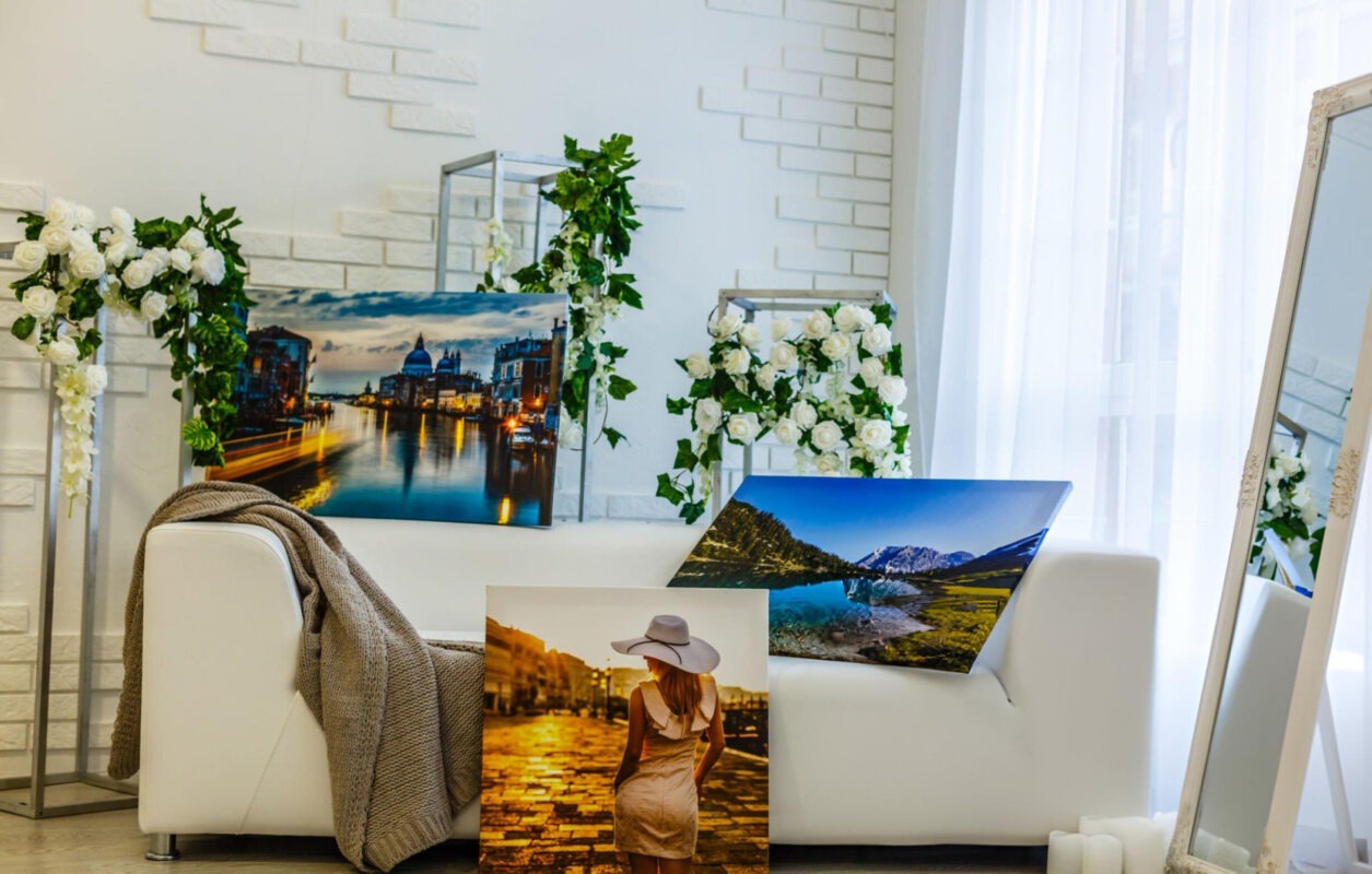 A canvas print of a white couch in a living room, with a mirror reflecting the scene. Paintings adorn the wall behind the couch.