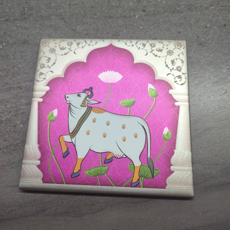 Pichwai-inspired ceramic tile featuring a white cow with a lotus flower on a pink background.