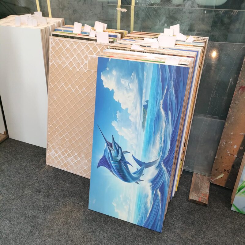 Assortment of ceramic tiles with various designs, including a prominent marlin image.