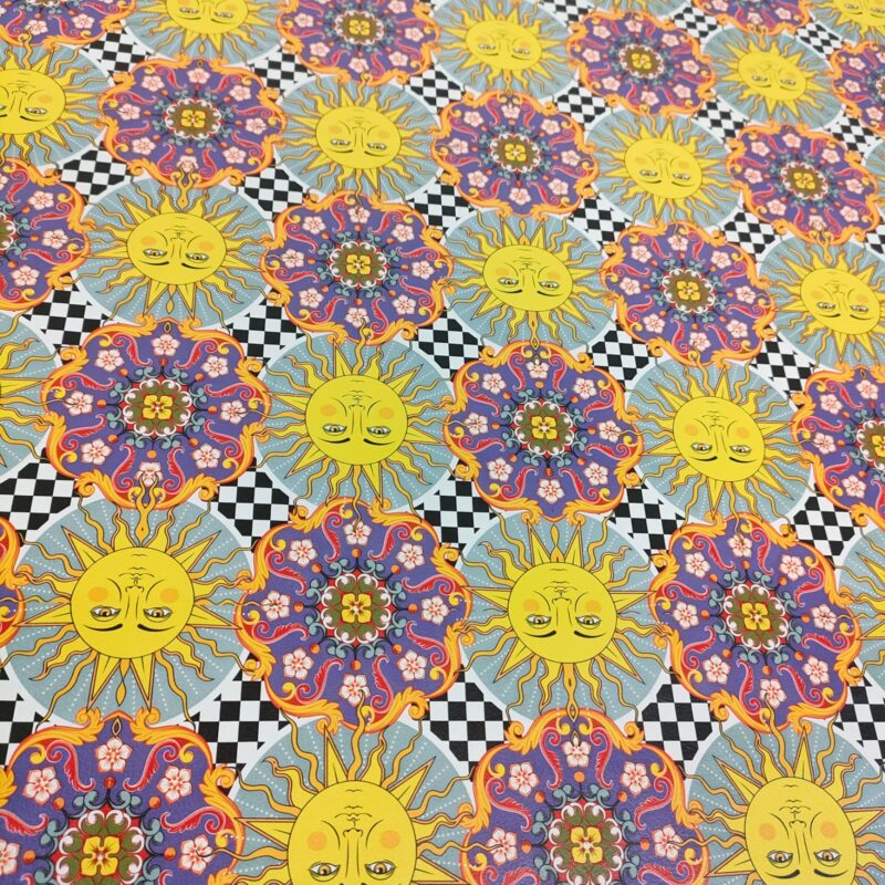 Repeating pattern of sun faces, floral motifs, and black and white checkered squares.