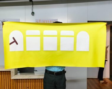 Yellow banner with five white rectangles and a red T-shaped symbol.