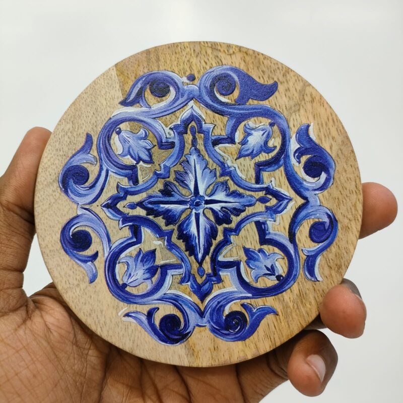 Round wooden coaster with a blue and white intricate floral design. printed on wood.