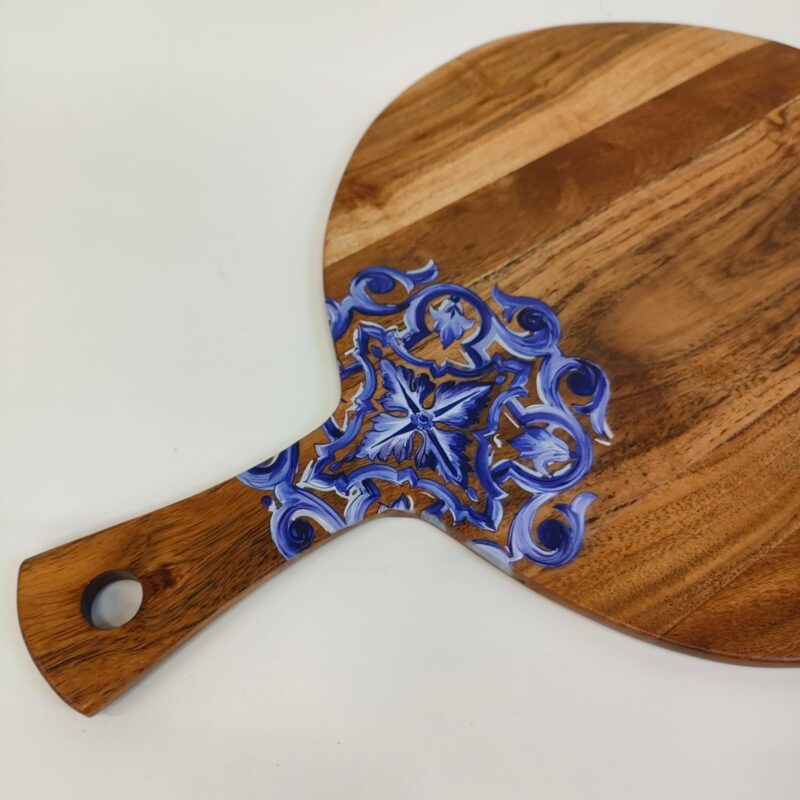 Round wooden serving board with a blue and white patterned handle and a natural wood edge.