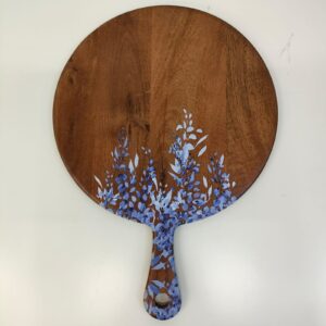 Round wooden serving board with a blue and white floral design, featuring a prominent handle