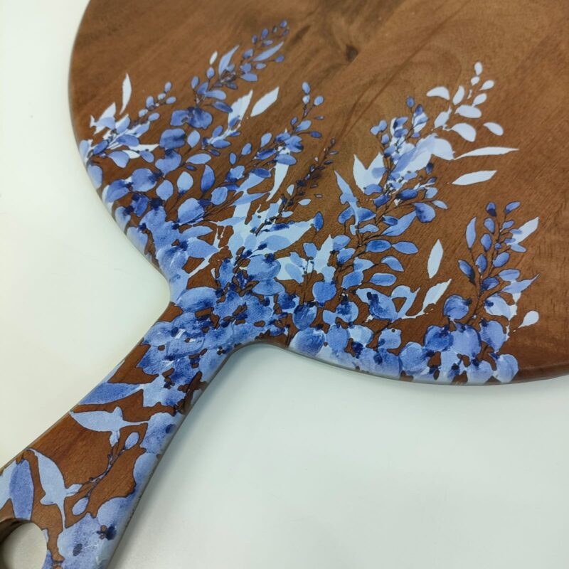 Round wooden serving board with a blue and white floral design, featuring a prominent handle