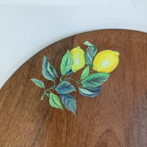 Close-up of a round wooden board with a vibrant UV-printed lemon branch design.