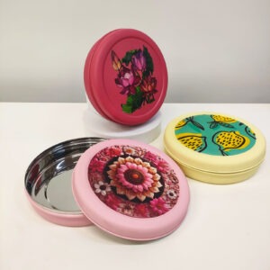 Three colorful tiffin lids with floral and fruit designs.