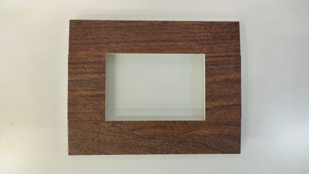 A square electrical switchboard cover with a woodgrain pattern.