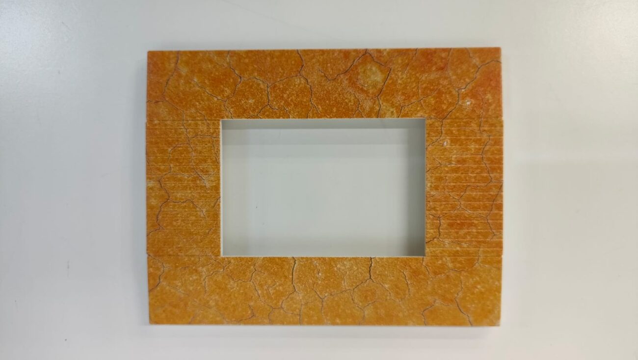 A square electrical switchboard cover with a unique orange and brown marble pattern