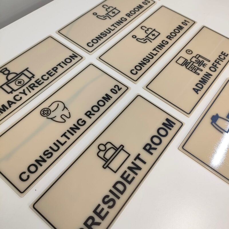 Multiple rectangular acrylic name plates with labels such as "MACY/RECEPTION," "CONSULTING ROOM," "RESIDENT ROOM," and "ADMIN OFFICE."