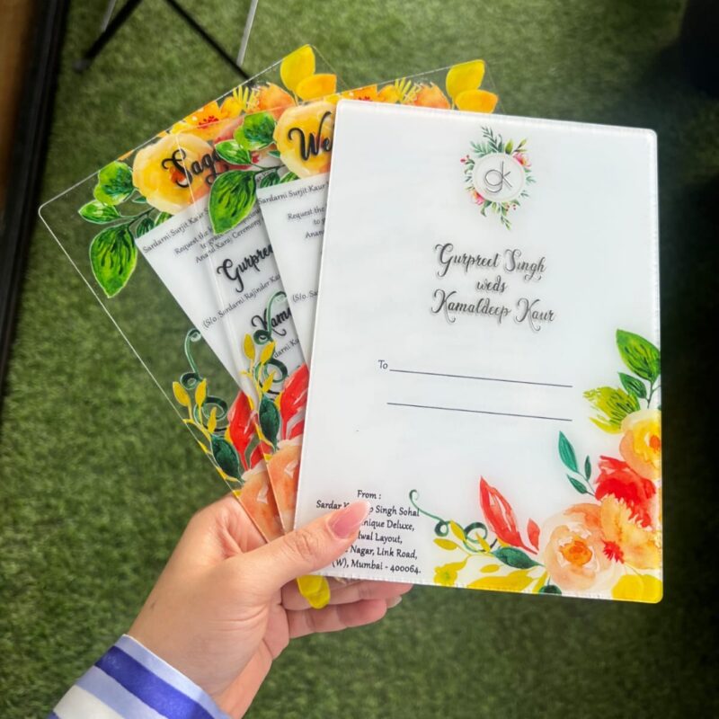 A person holding a stack of acrylic wedding cards with floral designs.