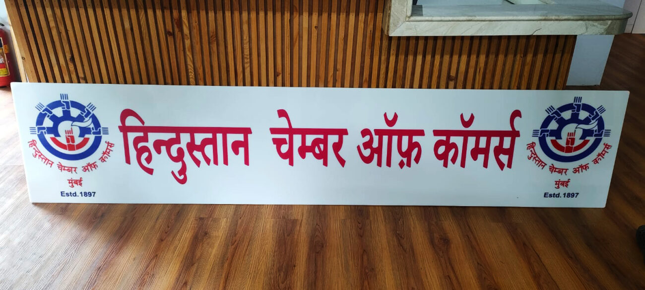 A rectangular acrylic signage board with red text on a white background.
